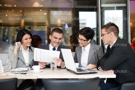 Group of four young business people gathered together at a table discussing an interesting idea in the cafe